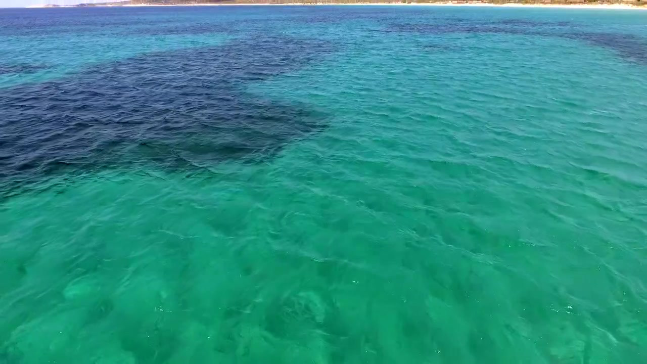 Vista aérea de águas oceânicas claras e turquesas e da costa litorânea