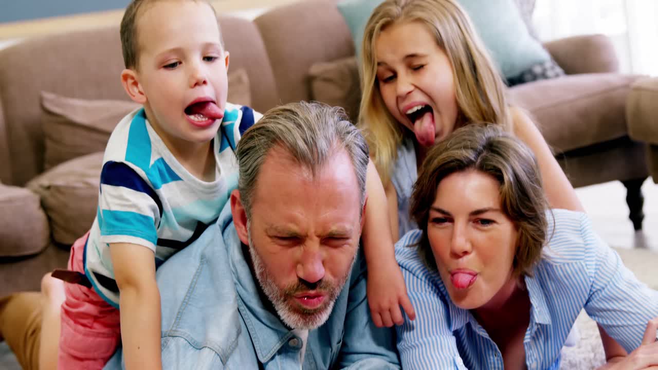 Glad familie ligger på et tæppe og tager en selfie med mobiltelefonen