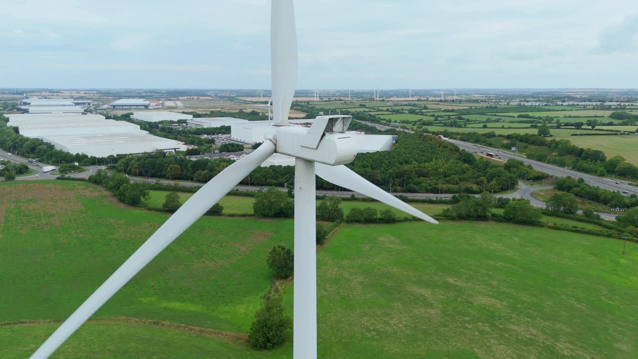 Aerial drone close up cinematic footage of wind turbines and industrial warehouses with factories and distribution centres near Lutterworth England UK
