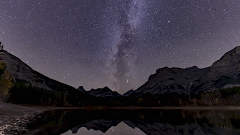 la vía láctea pasa a través de las montañas rocosas canadienses a lo largo de las aguas tranquilas de wedge pond, cerca de kananaskis, alberta.