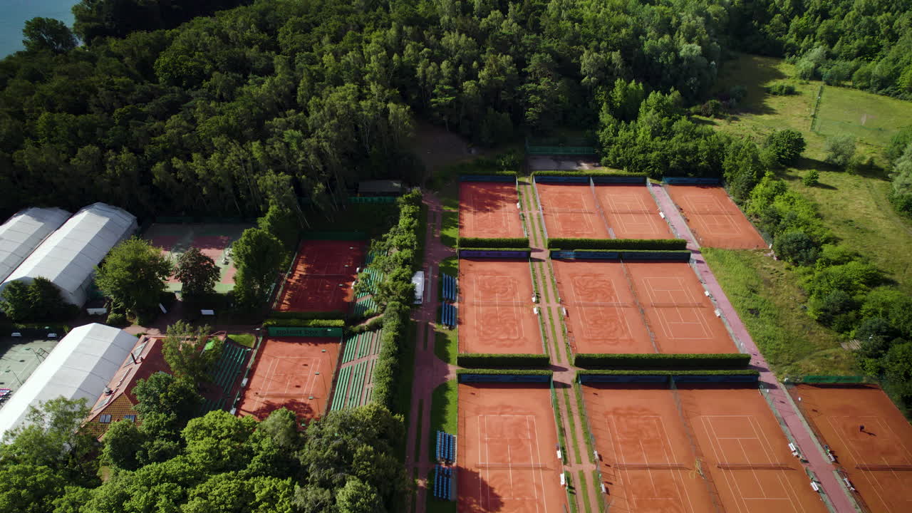 Vista aerea 4K di lussuosi campi da tennis in terra battuta rossa in una zona rurale.