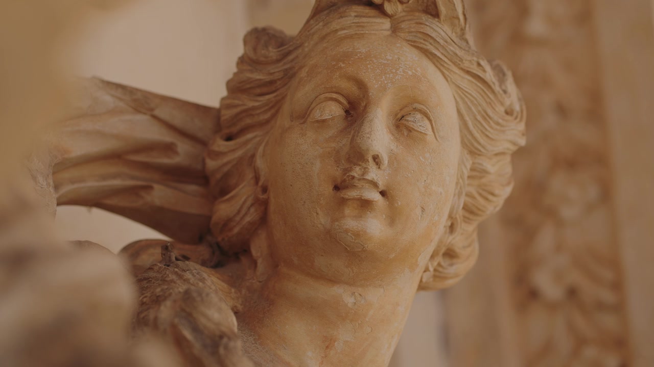 Primer plano del rostro de una escultura de piedra expresiva, capturando detalles intrincados en Coimbra, Portugal.