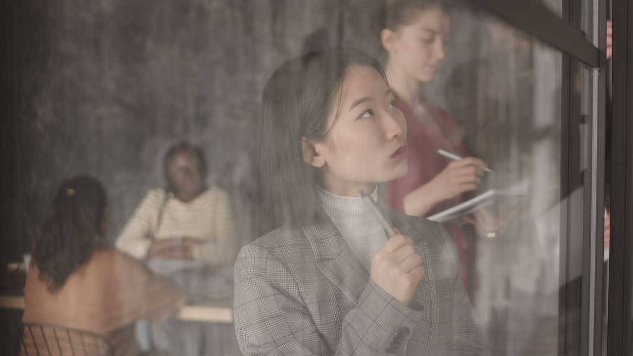 Pensive Asian Businesswoman Behind Glass Wall