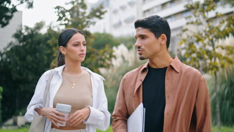 Relaxed-students-walking-park-close-up.-Woman-carrying-coffee-cup-listening-man