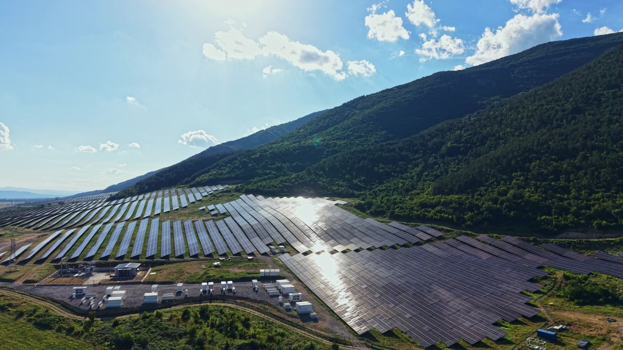 雲が浮かぶ晴れた日、田園地帯の山近くの土地を覆うソーラーパネルが太陽光を集めている