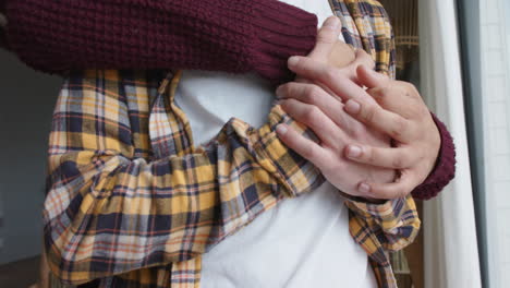 happy diverse gay male couple looking through window and embracing at home, slow motion