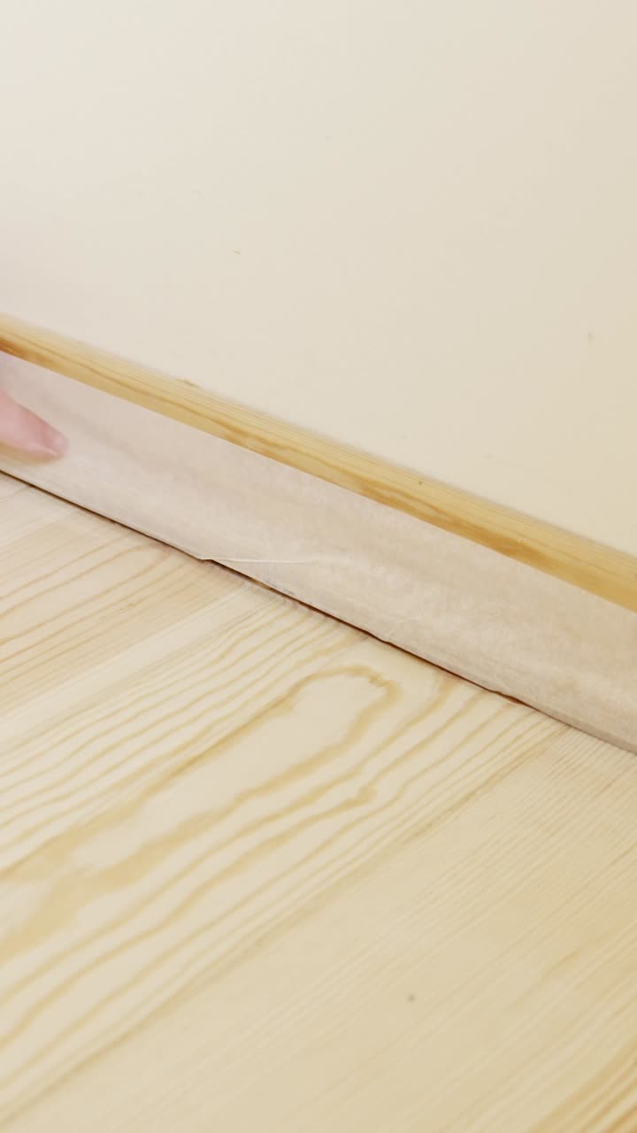 Installing wooden baseboard in a room, vertical renovation shot