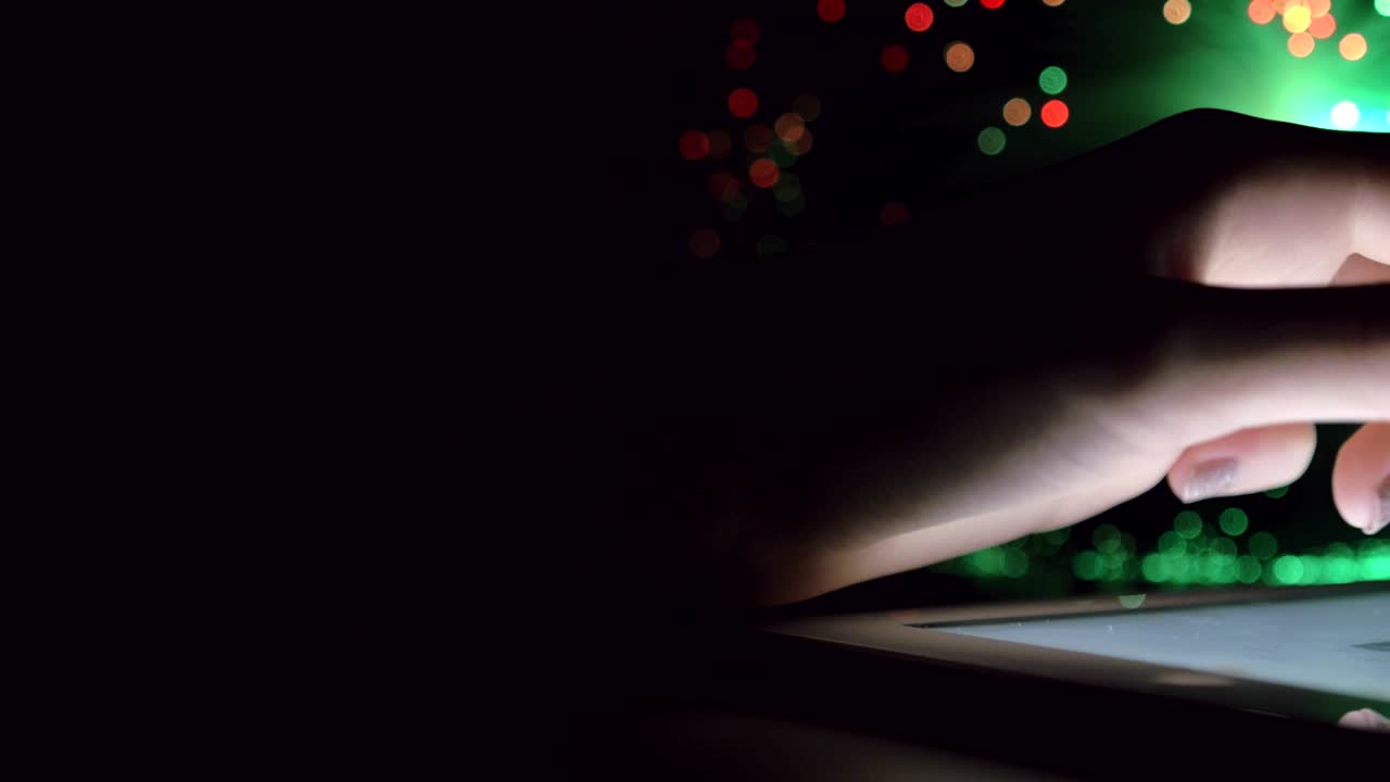 Woman Hand Touching And Browsing On Tablet Device In Dark Room With Colorful Blurry Fiber Optic Lights Closeup Panning Motion