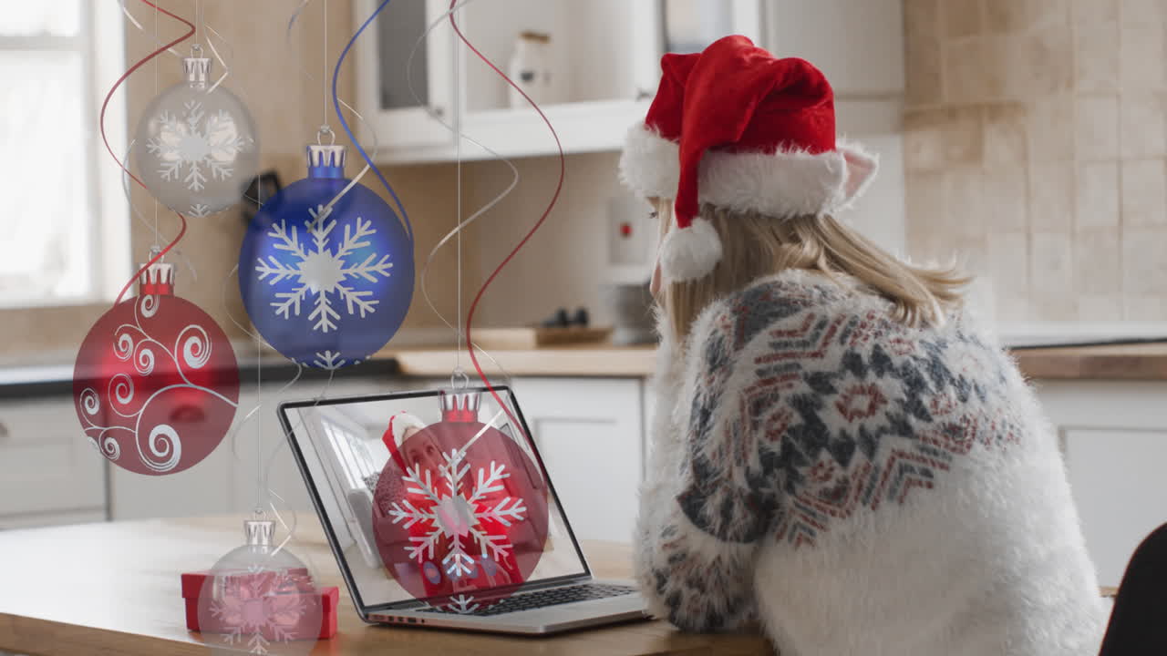 animación de bolas de navidad sobre mujer caucásica en sombrero de santa en portátil videollamada en navidad