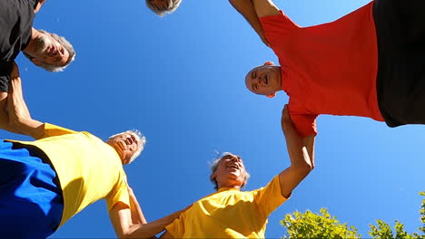 view from below of senior football players jumping in circle and clapping hands before workout