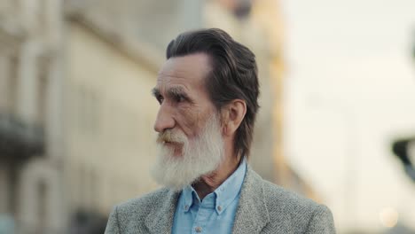 Portrait-Of-An-Elegant-Elderly-Man-With-A-White-Beard-And-Black-Hair-In-The-City-Looking-Straight-At-The-Camera