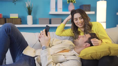 Happy-husband-and-wife-enjoying-spending-time-with-each-other-while-sitting-on-sofa-and-relaxing.