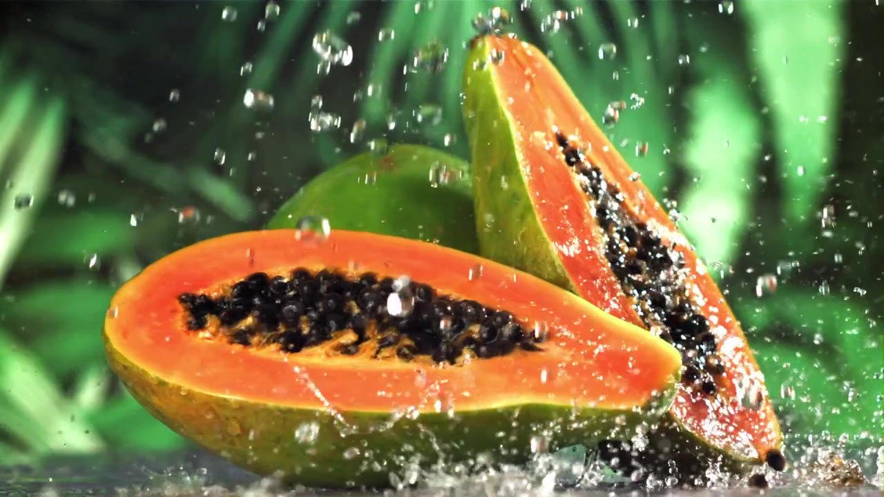 Friske papaya-halvdeler med sprutende vann i sakte film