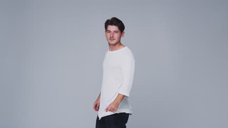 studio shot of man walking into frame against white background and dancing in slow motion