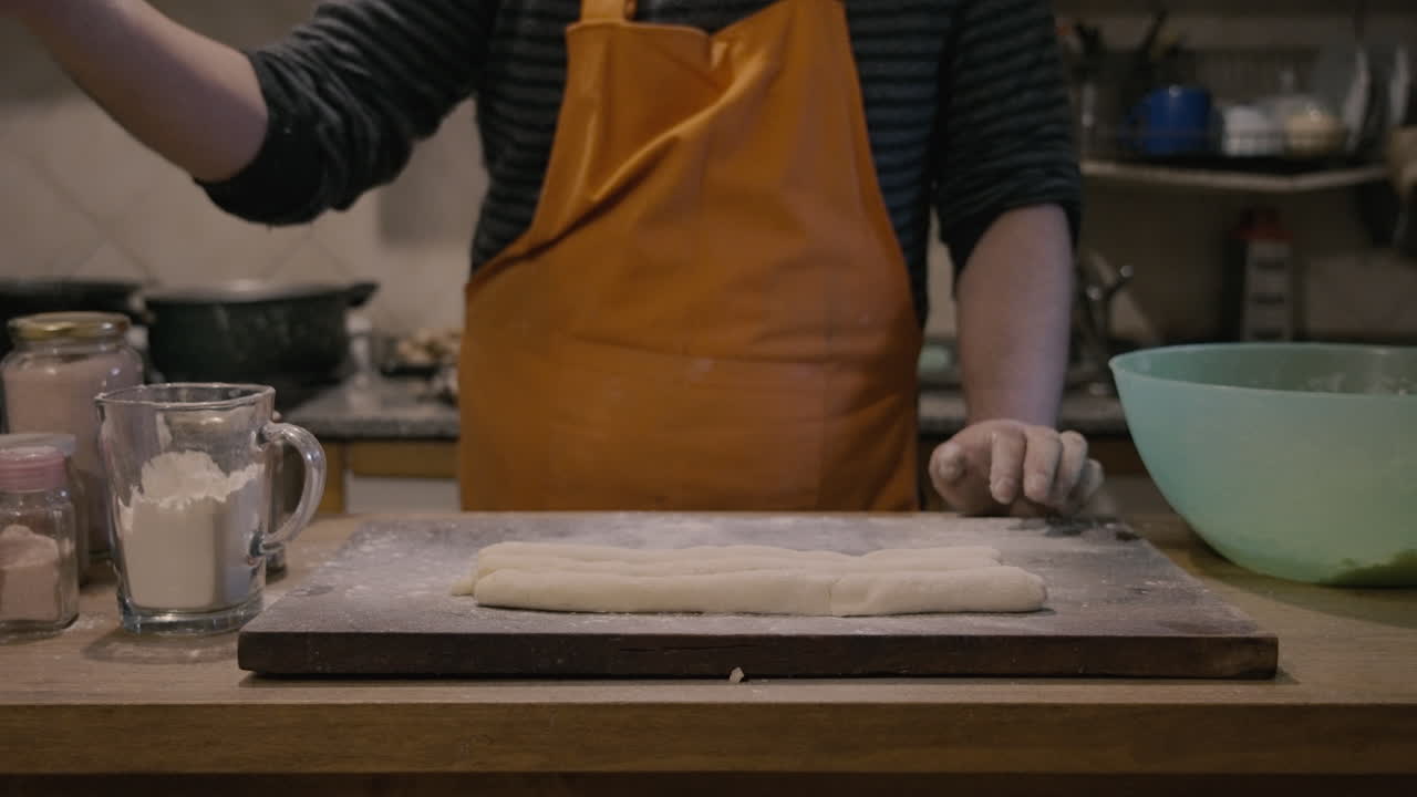 Person Sprinkling Flour on Dough in a Home Kitchen