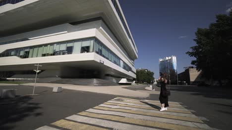 mujer caminando frente a un edificio moderno