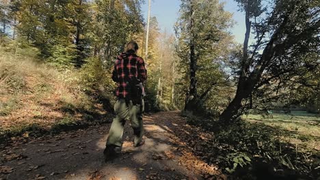 unknown male landscape photographer walking down the forest road and taking a picture in the distance