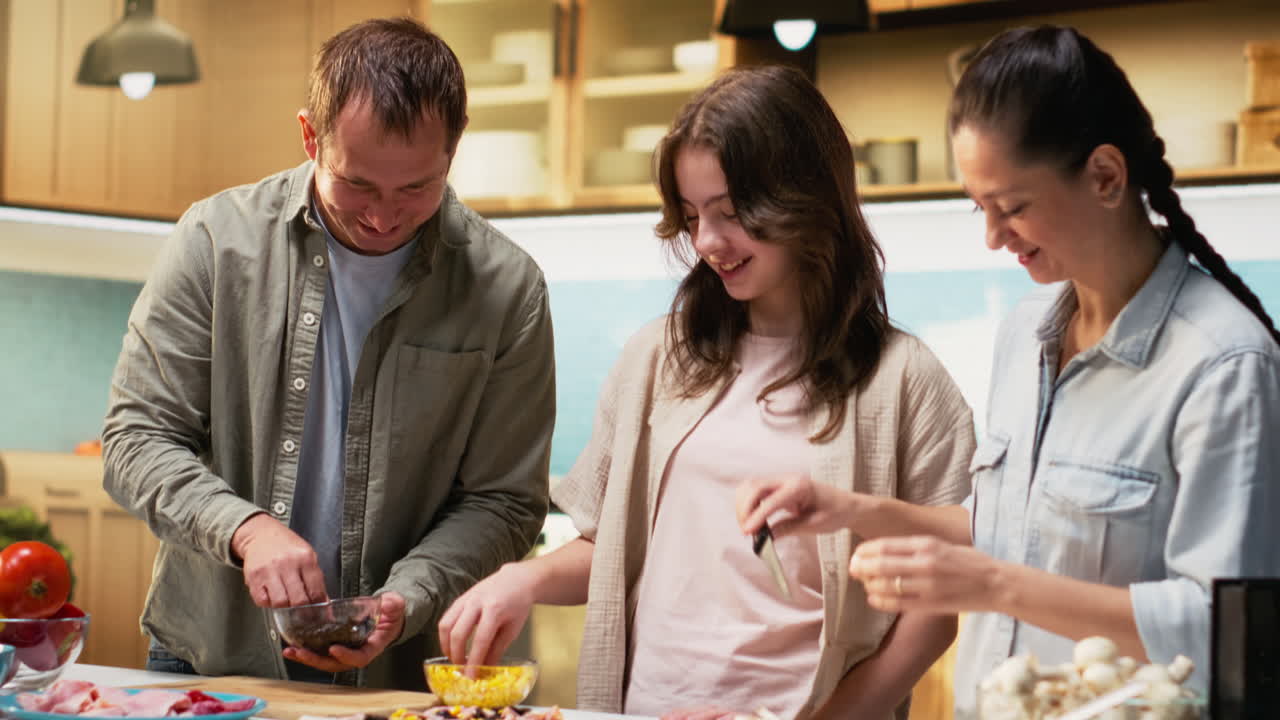 Family cooking homemade pizza together sprinkling ingredients and laughing