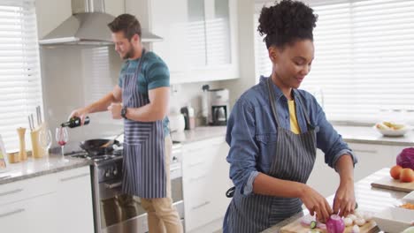 video of happy diverse couple preparing meal, cutting vegetables in kitchen