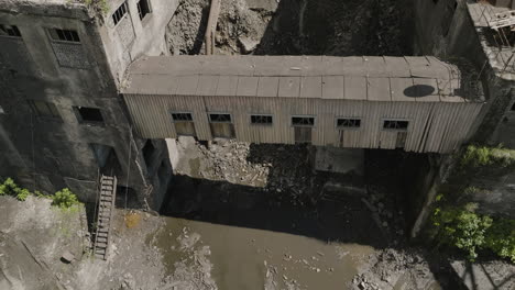 sheet metal skyway bridge between desolate buildings of abandoned mine