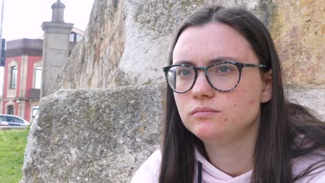 Young-girl-with-glasses-and-acne-eating-tangerine-pieces-on-the-street