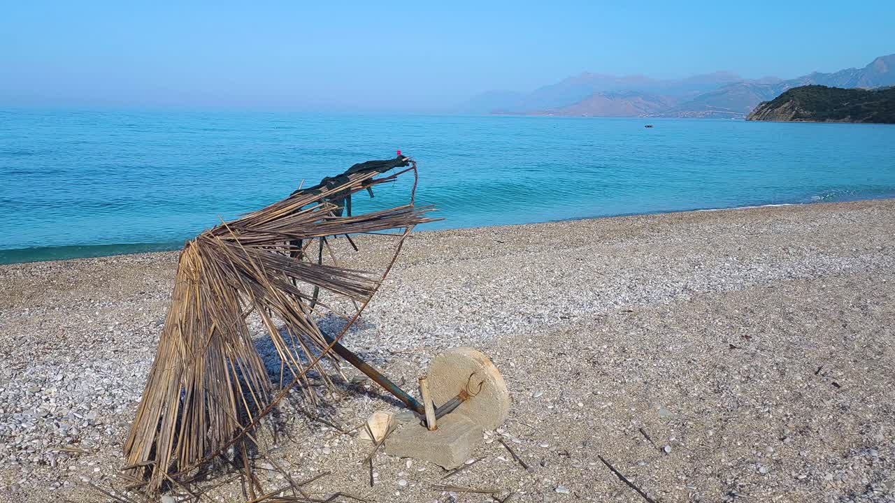 End of Summer Season: Abandoned and Damaged Straw Umbrella on an Empty Beach, Symbolizing the Season's Conclusion