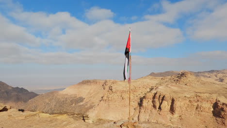 Jordaniens-Flagge-Weht-Im-Wind-Und-Fällt-Auf-Den-Fahnenmast,-Der-über-Den-Klippen-Von-Petra-Ragt