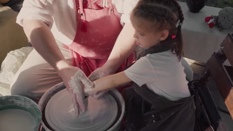 potter teaching pottery little girl