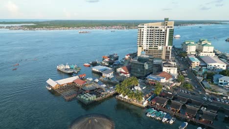 Toma-Aérea-De-Establecimiento-De-La-Plaza-Seafest-Con-Una-Vía-Fluvial-Muy-Transitada-En-Semporna