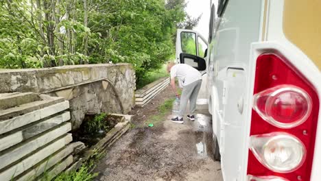 el viajero de la caravana recoge agua mineral natural gratuita del manantial del pueblo