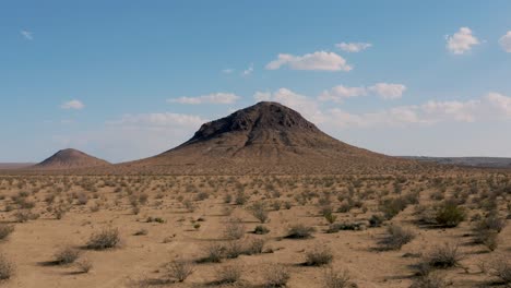 Flying-fast-toward-isolated-Mojave-Desert-mountain-on-sunny-day