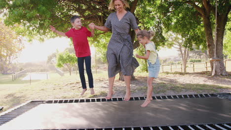 mother playing with children on outdoor trampoline in garden