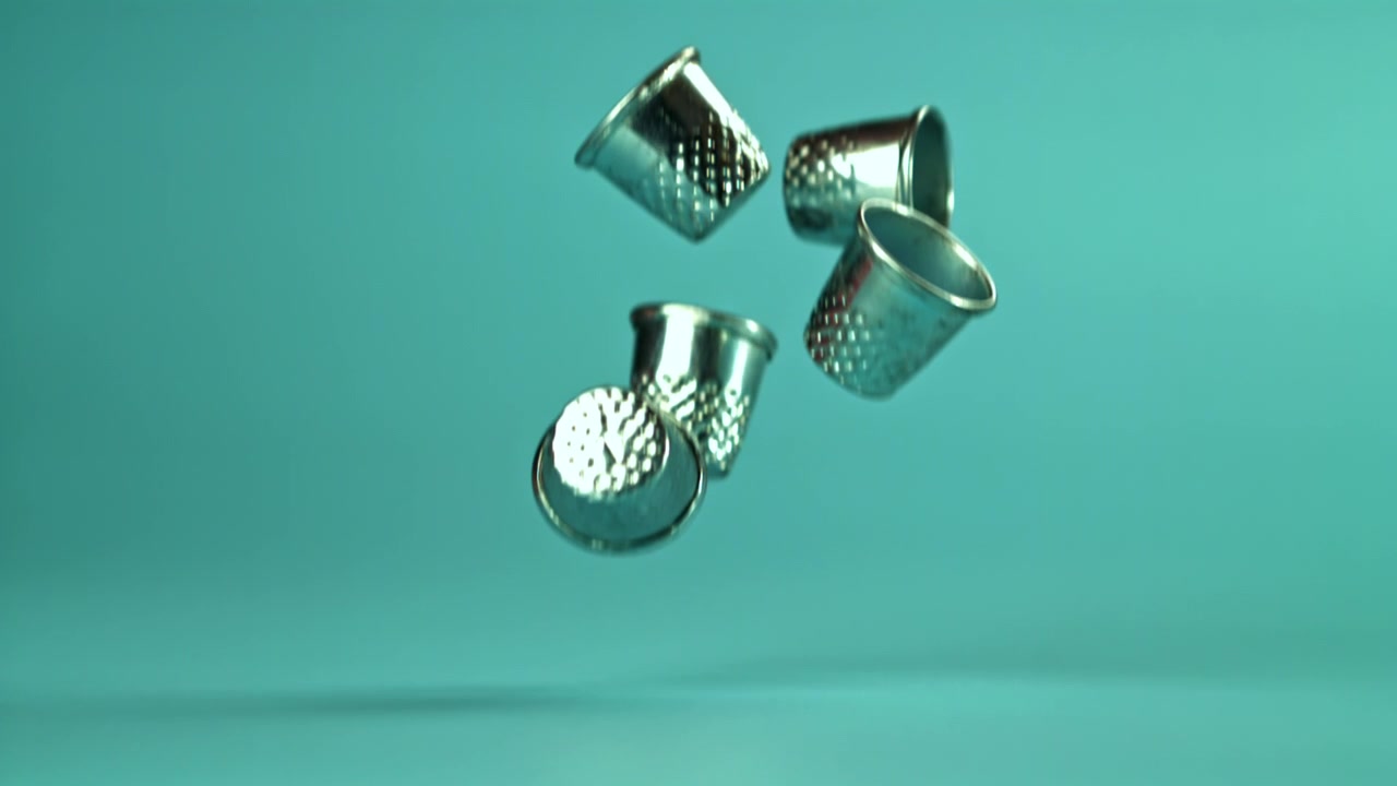 Silver Thimbles Falling in Slow Motion on a Blue Background