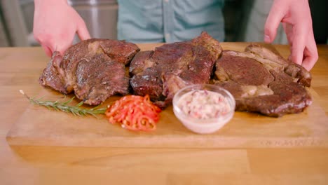 hombre con un bistec de ternera marinado a la parrilla sobre una tabla de madera colocada sobre la mesa lista para servir