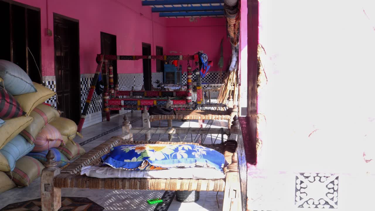 Charpai beds and sacks of grain standing on a porch in a rural village in Sukkur, Sindh, Pakistan