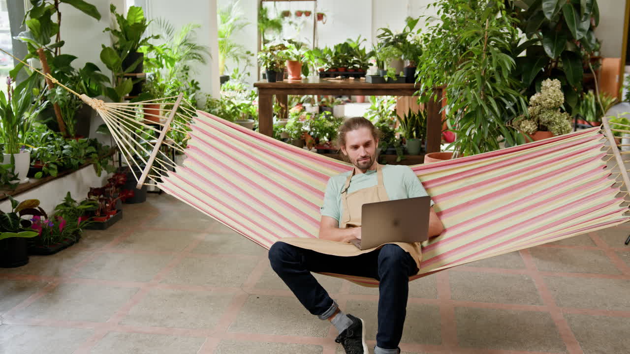 hombre trabajando en una tienda de plantas en una hamaca