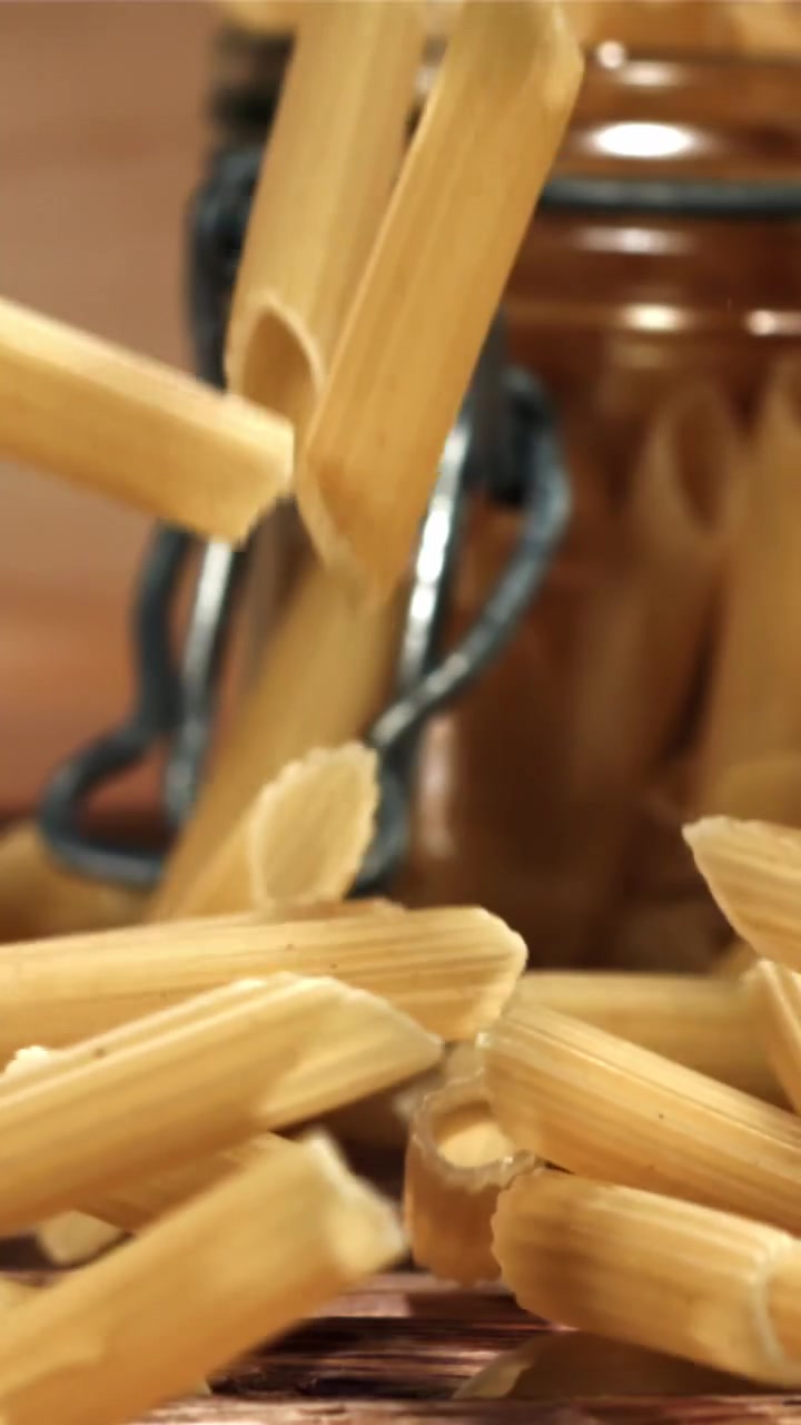 Penne che cadono al rallentatore su un tavolo di legno