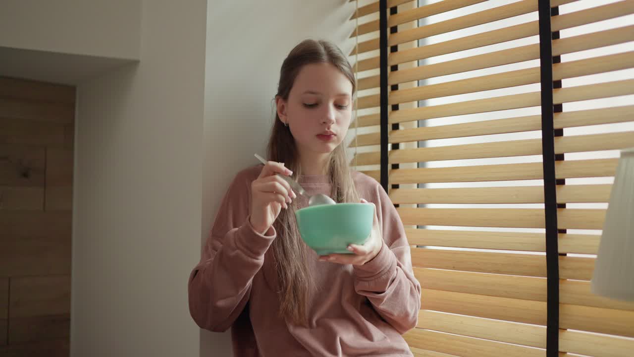 Girl eating from a bowl by the window