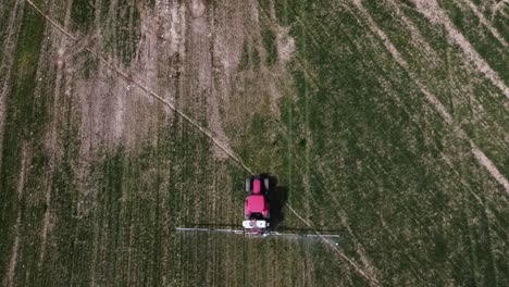 Vista-Aérea-De-La-Fumigación-De-Tractores-Agrícolas-En-El-Campo-Con-Rociador,-Herbicidas-Y-Pesticidas-Insecticidas-En-El-Campo-Verde-Tierra-Arada,-Tiro-Constante-De-Arriba-Hacia-Abajo