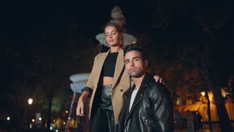 modelos de moda posando fuente de la ciudad en la noche oscura. pareja de moda sexy juntos