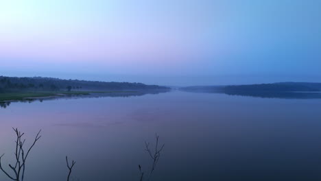 Morgens-Ruhiger-See,-Vor-Sonnenaufgang-Spiegelt-Sich-Der-See-In-Den-Atmosphärischen-Effekten-Des-Himmels-Und-Ist-Von-Nebligen-Nebeln-Umgeben