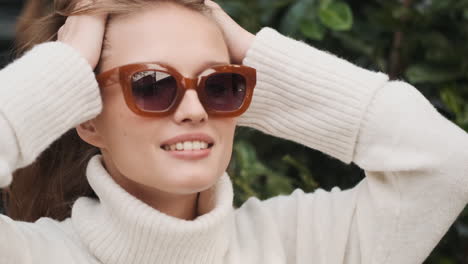 caucasian woman smiling in cozy sweater outdoors.