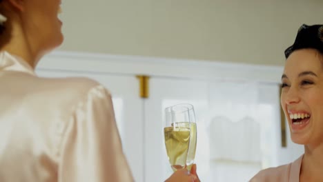 Excited-bridesmaids-in-nightdress-and-hair-rollers-toasting-a-glass-of-champagne-4K-4k