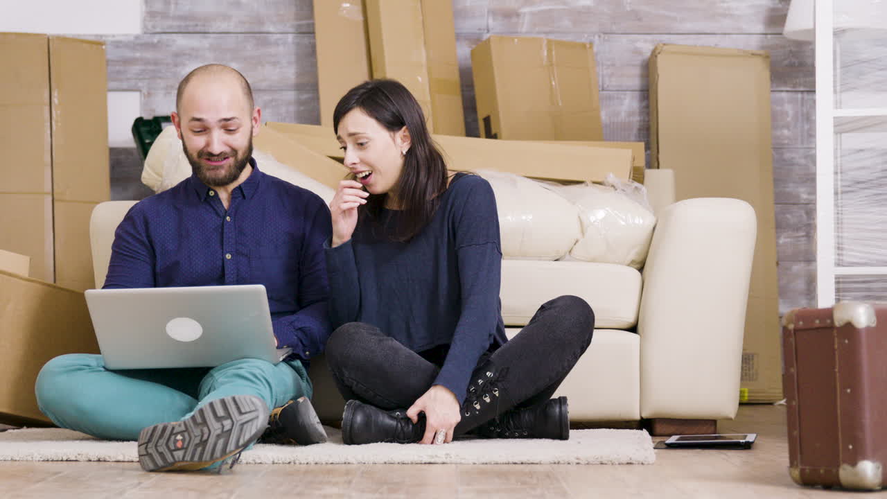 Couple with Laptop Surrounded by Moving Boxes