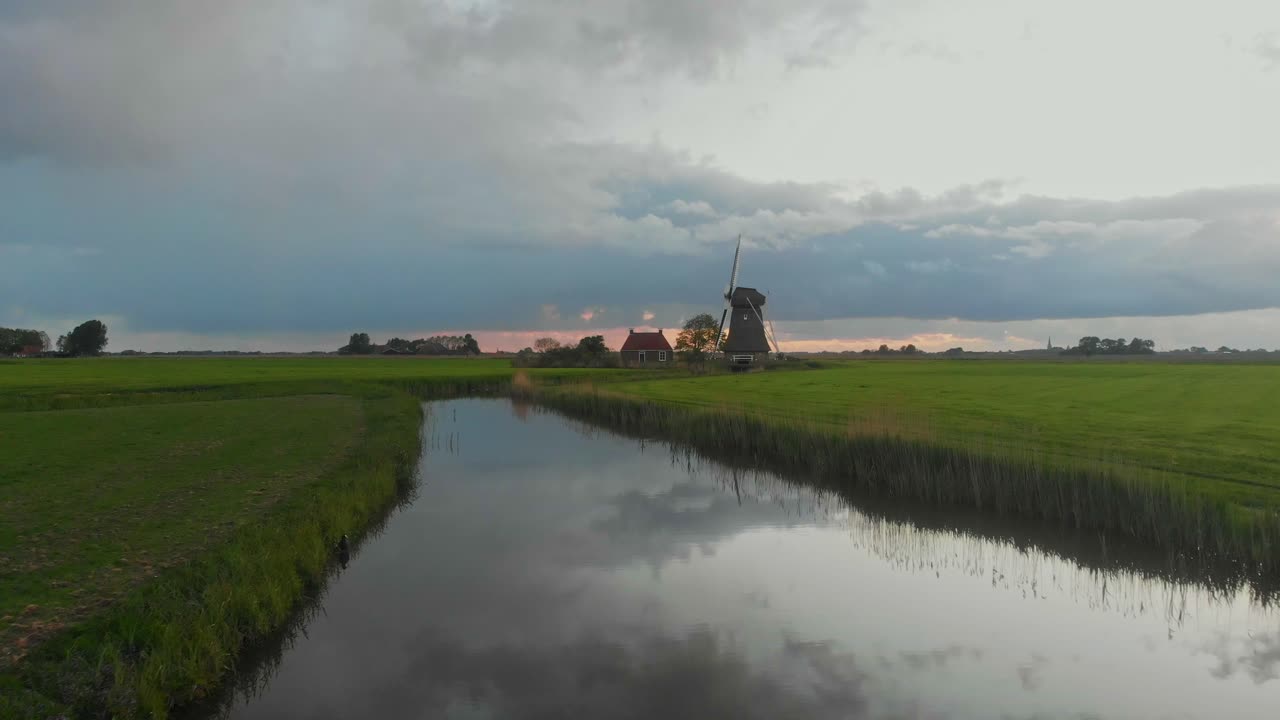 Vue aérienne d'un moulin traditionnel avec une maison et un fossé au lever du soleil à Lollum, Frise, Pays-Bas