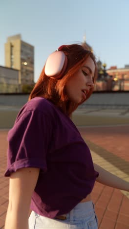 woman dancing in the city during sunset with headphones