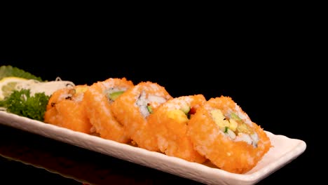 a rectangular plate of california roll sushi rotates smoothly under bright studio lighting, highlighting vibrant colors and fresh ingredients against a glossy black background