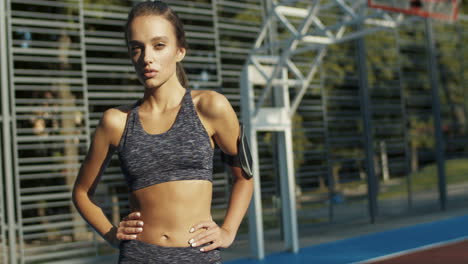 Porträt-Einer-Sportlichen-Frau,-Die-Fröhlich-In-Die-Kamera-Lächelt,-Während-Sie-An-Einem-Sommertag-Auf-Dem-Sportplatz-Steht