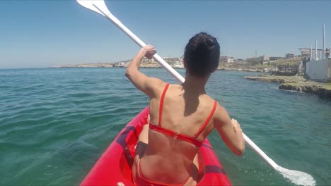Vista-Posterior-Mujer-Activa-En-Bikini-Rojo-Kayak-En-El-Mar-En-Verano