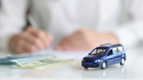 toy blue car and money in background woman fills out application